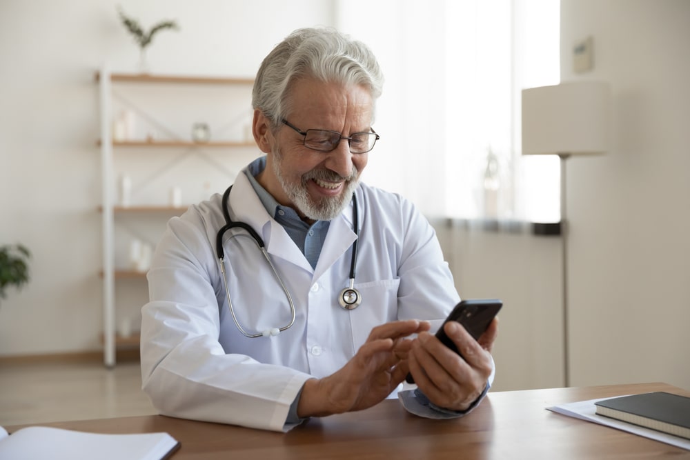 happy-old-doctor-holding-smart-phone